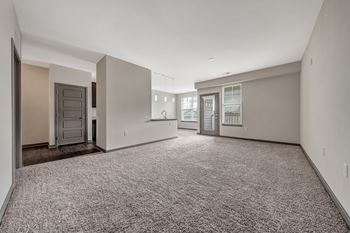 A spacious empty room with carpeted floor and white walls.